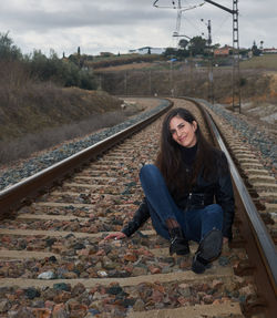 A beautiful young girl sitting quietly on the train rails.