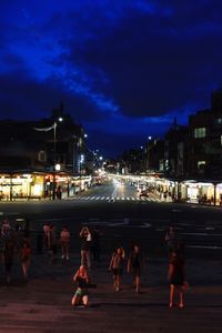 People on street against illuminated city at night