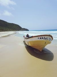 Boat moored on beach against clear sky