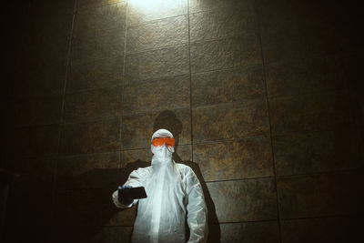 Man using phone while standing against wall