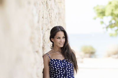 Beautiful young woman standing against wall