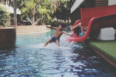 Shirtless boy playing on slide at water park