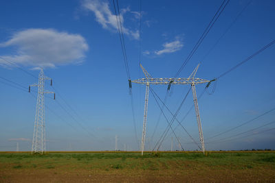 Row of transmission lines against blue cloudy sky