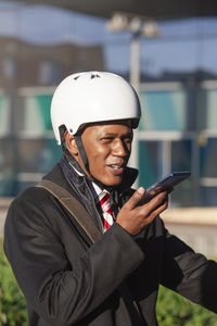  businessman in a scooter helmet holds the phone and smiles while talking on voice messaging