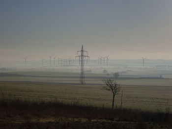 Electricity pylon on field against sky