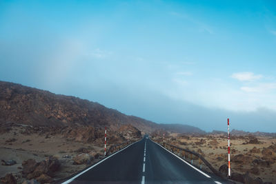 Road leading towards mountain against sky