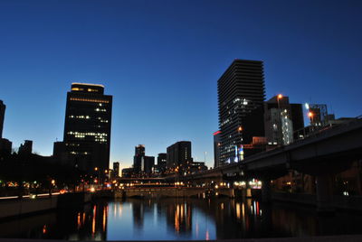 Low angle view of illuminated buildings against blue sky