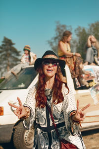 Happy young woman wearing sunglasses against sky