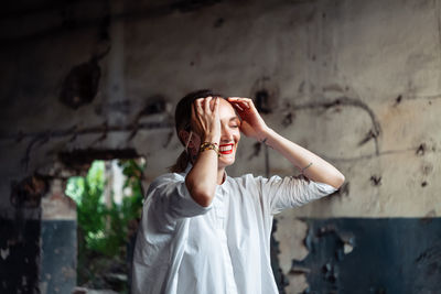 Young fashionable woman in a white shirt in an old abandoned decaying building