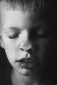 Close-up of boy with eyes closed touching nose on glass window at home