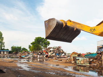 Low angle view of excavator against cloudy sky