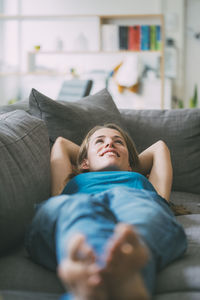 Smiling young woman lying on couch at home