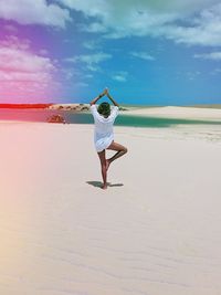 Rear view of woman practicing yoga at beach