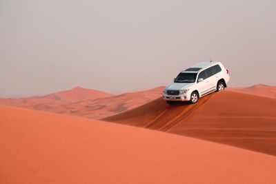 Car on desert against sky