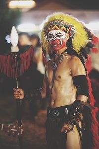 Man looking away while wearing tribal costume at night