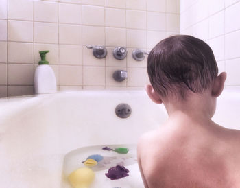 Rear view of shirtless man in bathroom