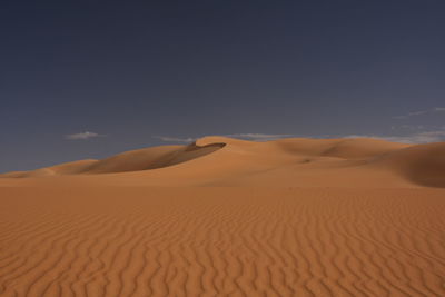 Sand dunes in desert against sky