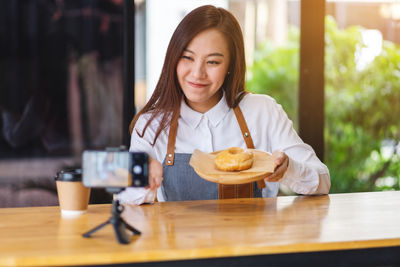 Portrait of young woman using mobile phone while sitting on table