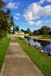 Footpath by lake against sky