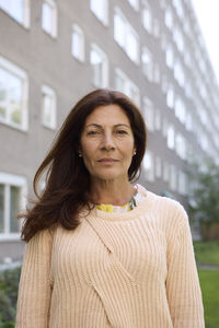 Mature woman looking at camera, block of flats in background