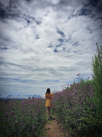 Rear view of woman standing on field against sky