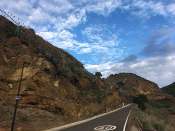 Road by mountain against sky