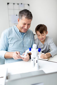 Father with son playing with robot at home