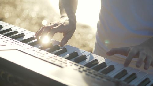 Midsection of musician playing piano synthesizer