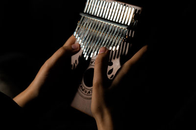 Midsection of person holding guitar against black background