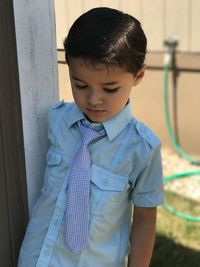 Boy wearing necktie while standing by wall
