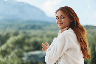 Portrait of young woman standing against sky