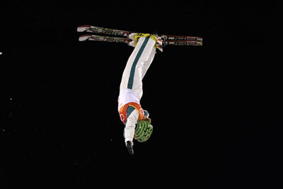 Man with arms raised against black background