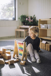 Girl learning to count through abacus while sitting in classroom at kindergarten