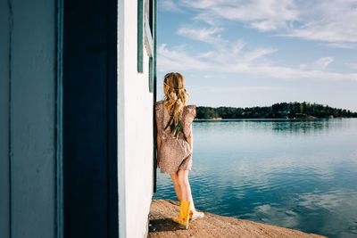 Young girl standing alone looking out at the ocean thinking