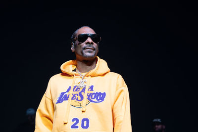 Portrait of man wearing sunglasses standing against black background