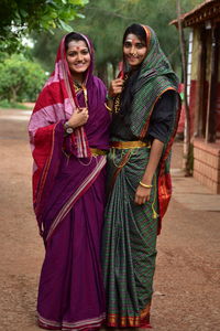 Portrait of smiling young women in traditional clothing standing outdoors