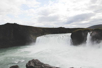 Scenic view of waterfall against sky