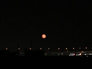 Defocused image of illuminated lights against sky at night