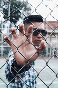 Close-up of man holding chainlink fence