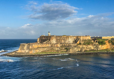 Scenic view of sea and fortress against blue sky surrounded by ocean. 