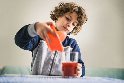 Cute boy pouring juice in glass at home
