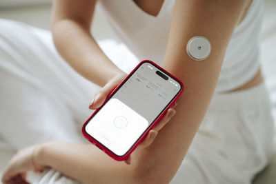 Woman measuring sugar level through smart phone at home