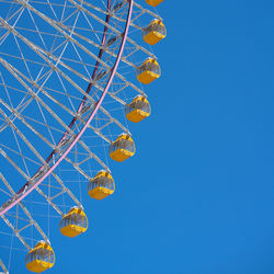 Low angle view of ferris wheel against clear blue sky