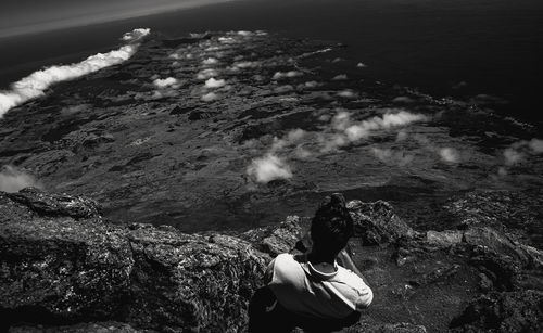 Rear view of woman sitting on rock