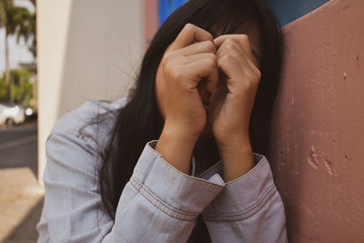 Close-up of woman covering face with hand