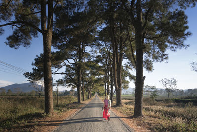 Rear view of woman on road amidst trees