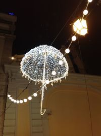 Low angle view of illuminated light bulb against sky at night