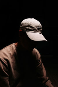 Portrait of person wearing hat against black background