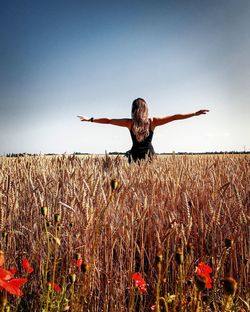 Rear view of woman on field against clear sky