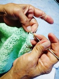 Cropped hands of person knitting at home